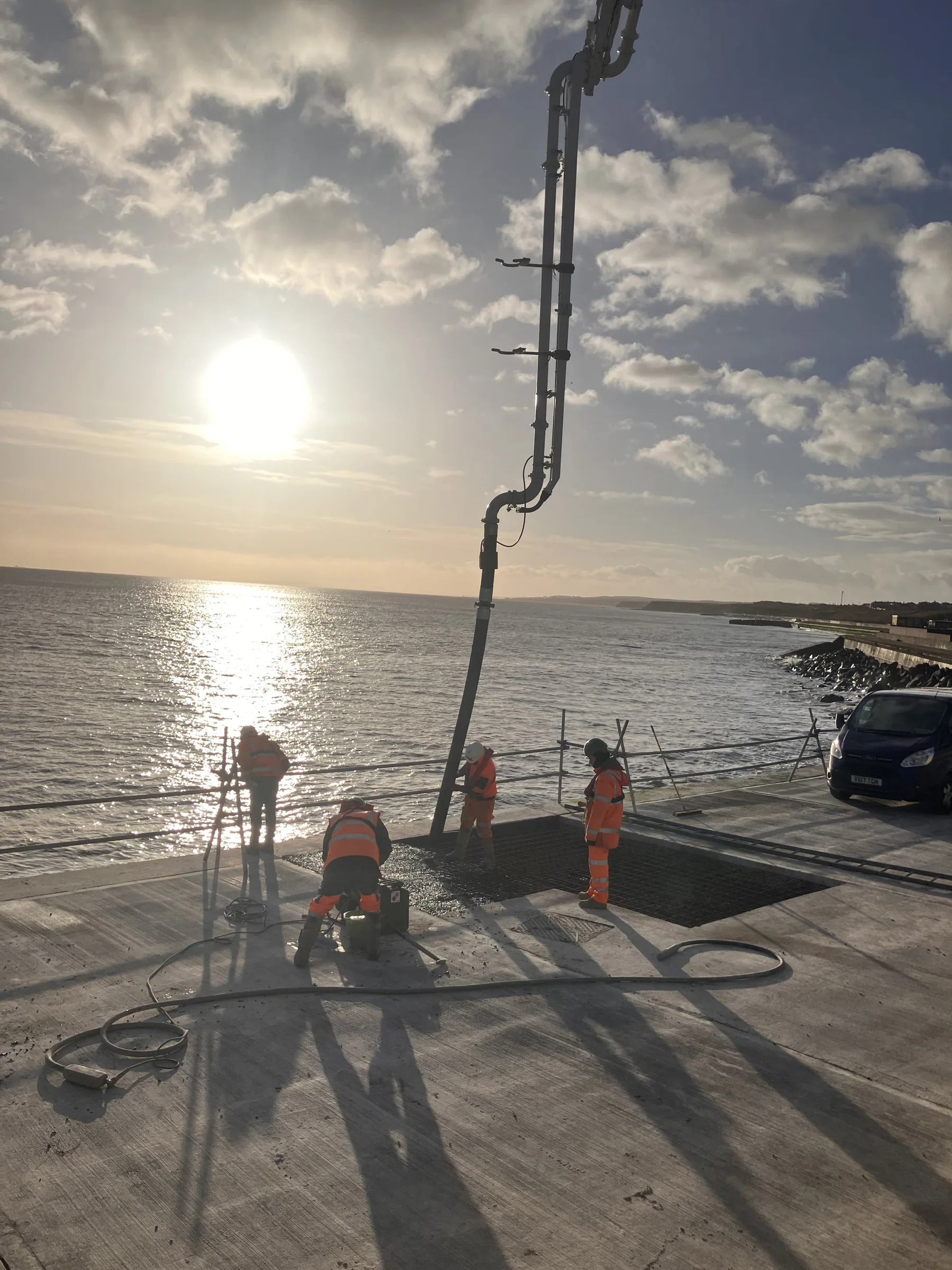Concrete pump delivery hose extended towards coastal repair works beside the North Sea at Sunderland